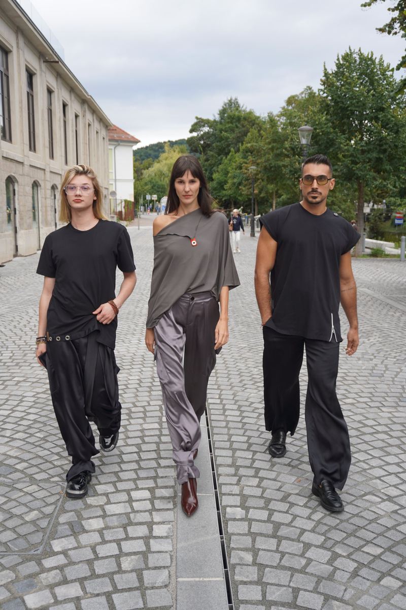 Trije modeli v črnih in sivih kosih hodijo po Ljubljani